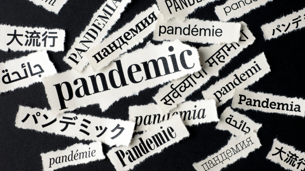 The image depicts the word "pandemic" in various languages printed on torn pieces of paper, scattered across a dark surface, symbolizing the post-pandemic world unraveling with challenges and opportunities.